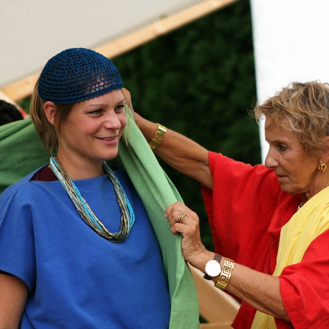 Frau hilft Jugendlicher beim Einkleiden (beide in römischem Gewand)