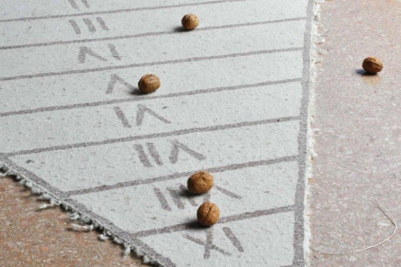 Römisches Wurfspiel: Teppich in dreieckiger Form mit bezifferten Feldern und Haselnüssen
