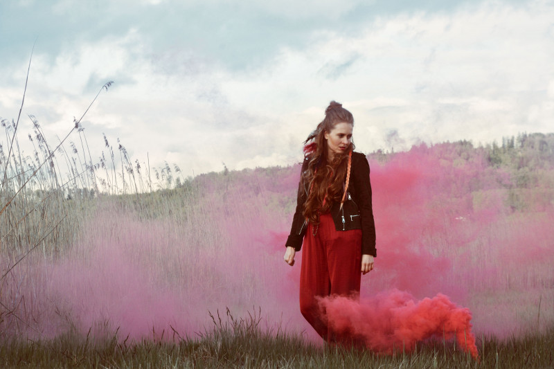 Musikerin Moira auf Wiese umgeben von pinkem Nebel