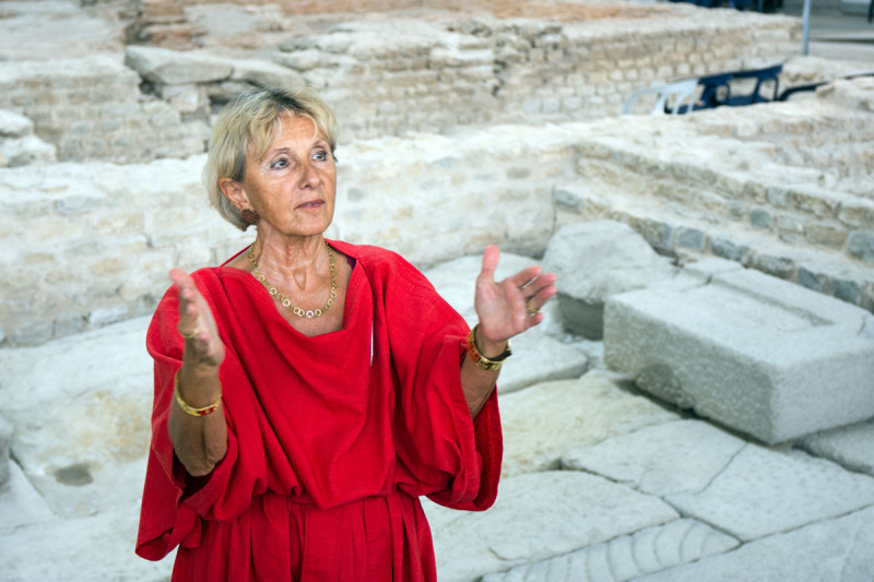 Gästeführerin in rotem römischen Gewand in den Kleinen Thermen