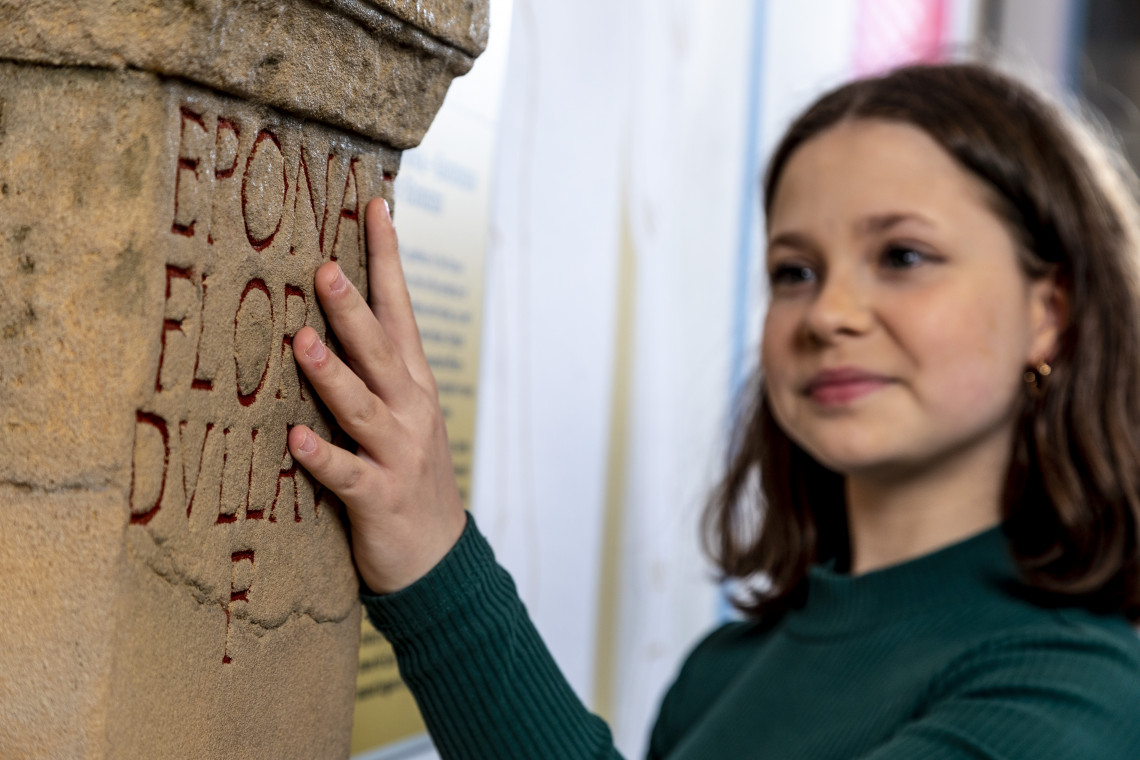Mädchen ertastet Inschrift an Taststation Weihestein