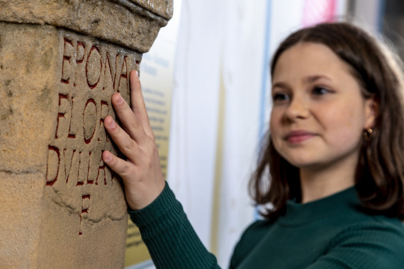 Mädchen ertastet Inschrift an Taststation Weihestein