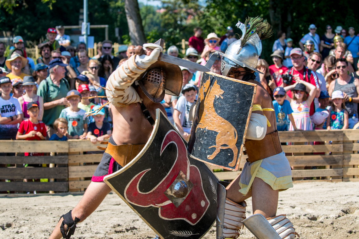 Two gladiators fight in arena in front of spectators