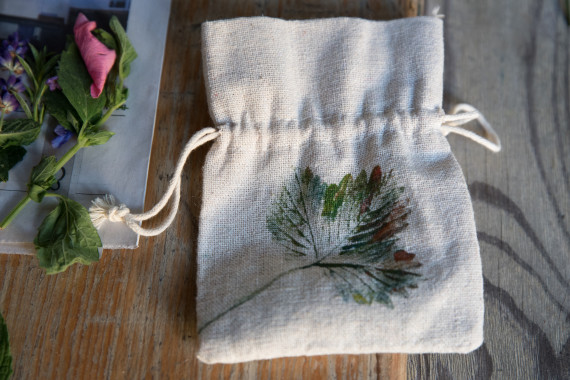 Getrocknete Kräuter und Blüten in Glasröhrchen, darunter Mörser